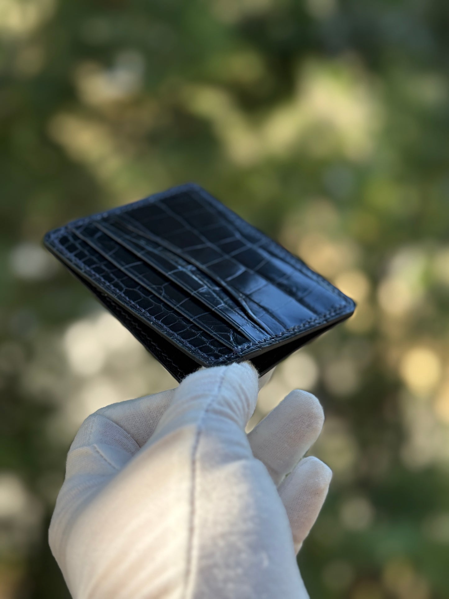 
                  
                    Three-quarter angle of a navy glazed alligator card holder showing its slim profile and layered card slots.
                  
                