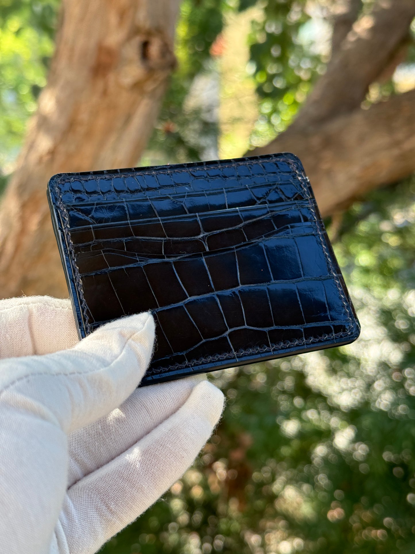 
                  
                    Close-up of glossy navy alligator leather showing distinct scale patterns and hand-burnished edge finishing.
                  
                
