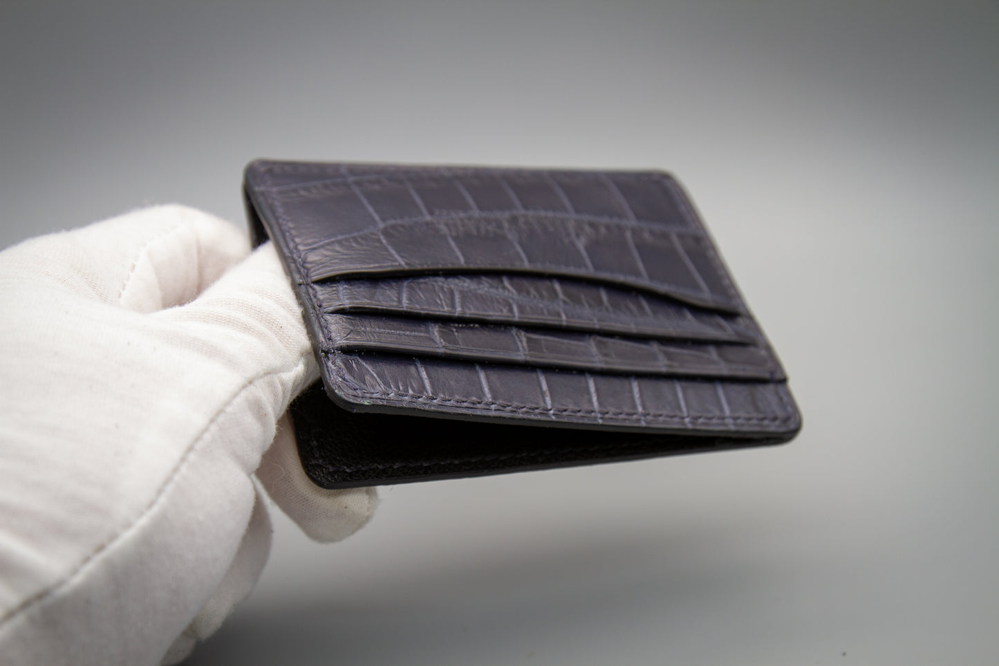 
                  
                    Macro detail shot of the hand-burnished edge and structural stitch lines on a matte navy alligator card holder.
                  
                