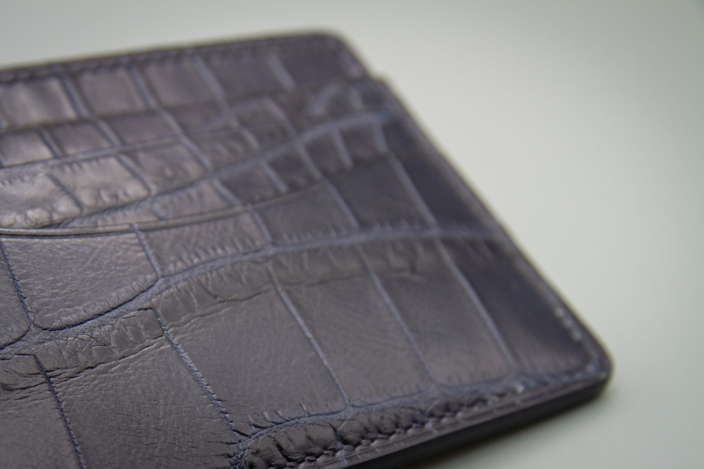 
                  
                    close up on the unique scale pattern of the matte navy alligator cardholder
                  
                