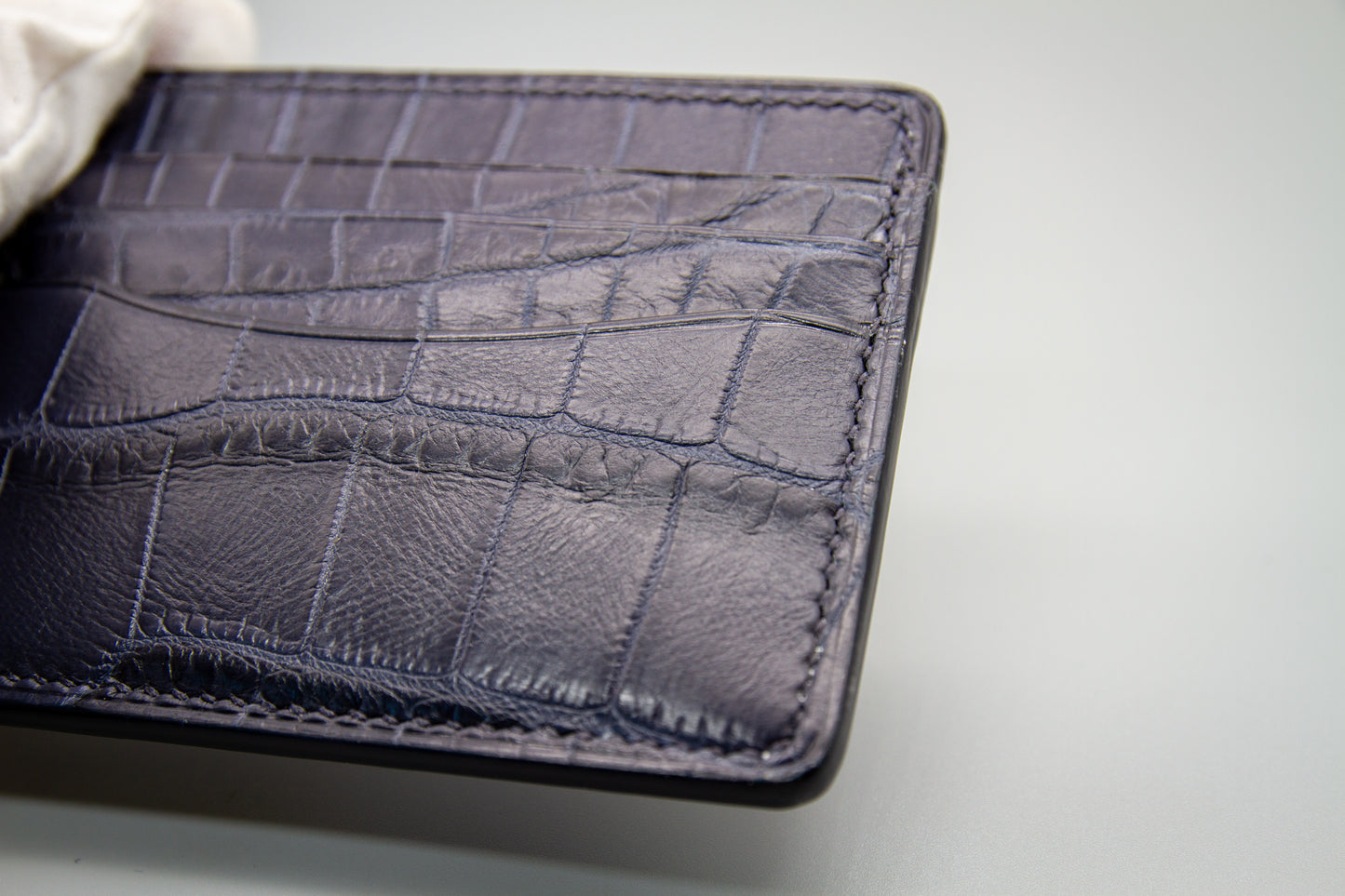 
                  
                    Close-up of matte navy alligator leather highlighting the natural scale grain, precise stitching, and smooth edges.
                  
                