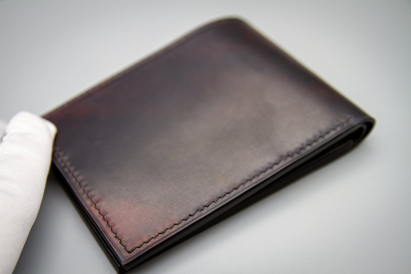 
                  
                    Top-down flat lay of closed marbled shell cordovan leather wallet
                  
                