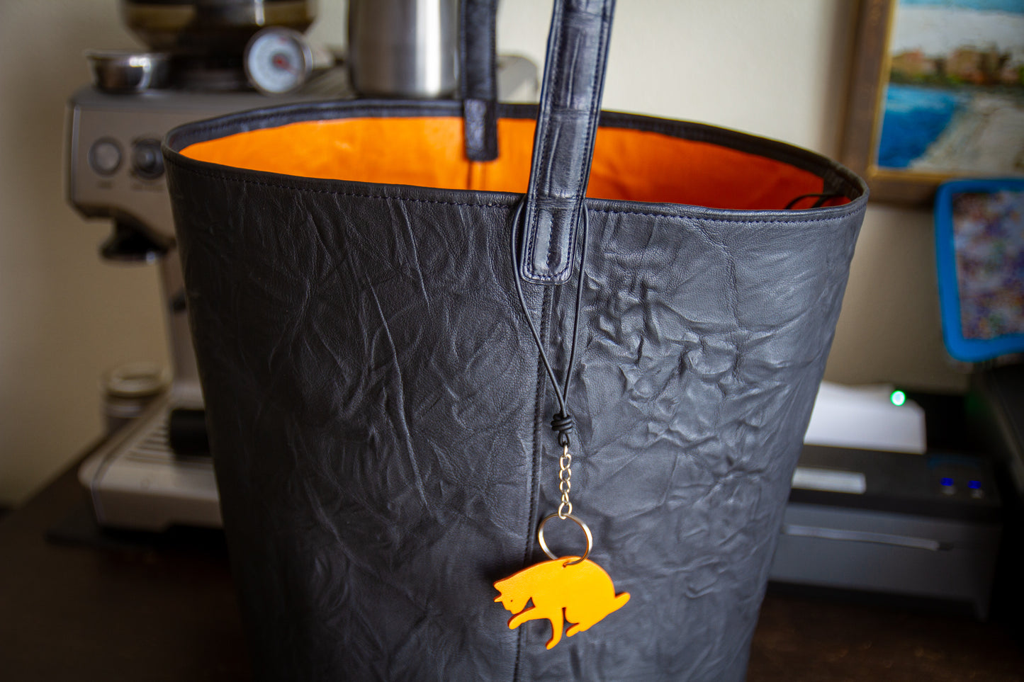 
                  
                    Close-up of the embossed leather shoulder strap attachment and reinforced stitching along the top rim
                  
                