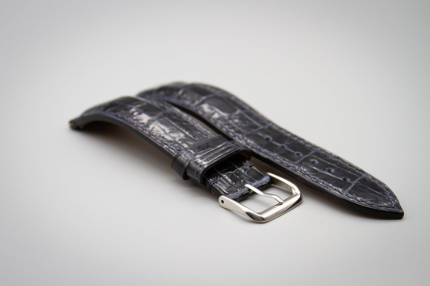 
                  
                    Glossy midnight blue alligator leather watch strap detail shot
                  
                