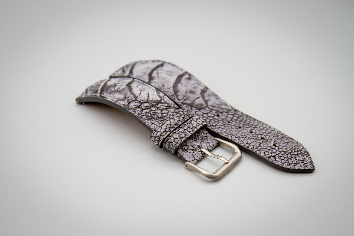 
                  
                    Pre-Curved Stone washed grey ostrich leg leather watch strap on craftsman workbench
                  
                