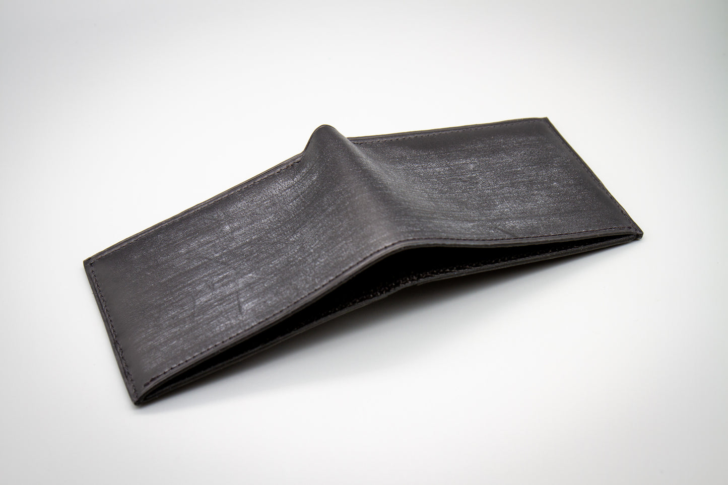 
                  
                    Back exterior view of closed Italian Belfagor leather bifold wallet featuring rich veg-tan texture
                  
                