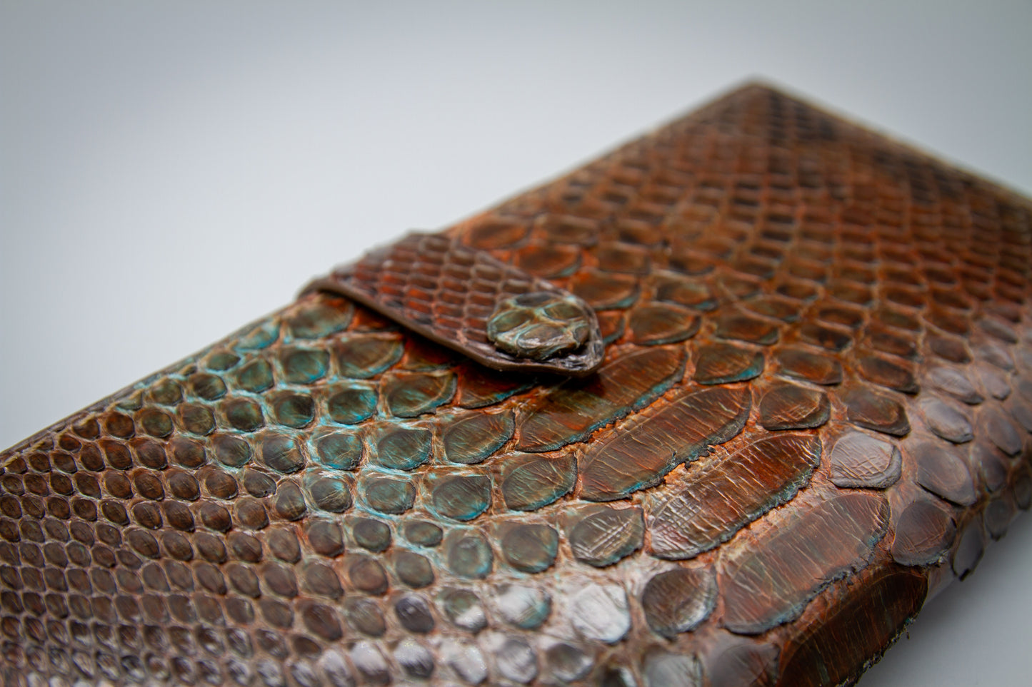 
                  
                    Macro shot of the brass snap button set on the exterior python leather
                  
                