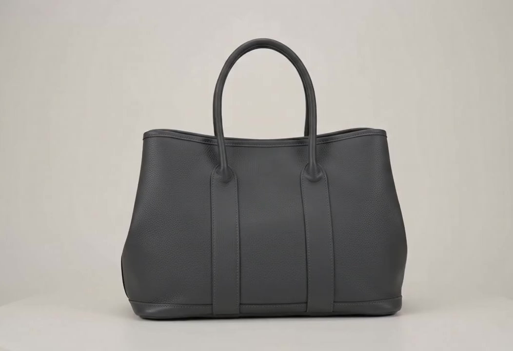 
                  
                    Load and play video in Gallery viewer, 360-degree rotating view of a handcrafted gray Togo leather voyager tote bag showing all exterior angles, base, and rolled handles.
                  
                